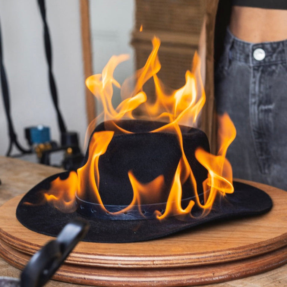Flaming black hat on a wooden surface with a blurred background